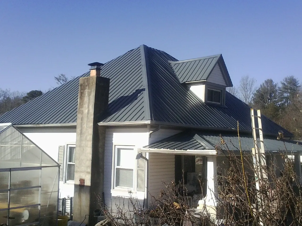Dark blue standing seam metal roof on a white farmhouse with dormer — Slate & Tile Roof Repair by Roofing Brothers in Allendale