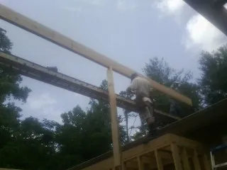 Carpenter setting a ridge beam over a new addition frame — Ice Dam Removal by Roofing Brothers in Allendale