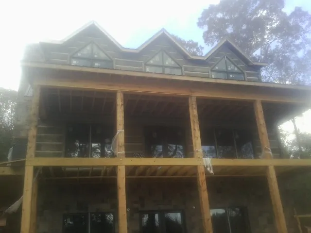 Dormers and porch framing on a large log home under construction — Roof Coating work by our crew in Allendale